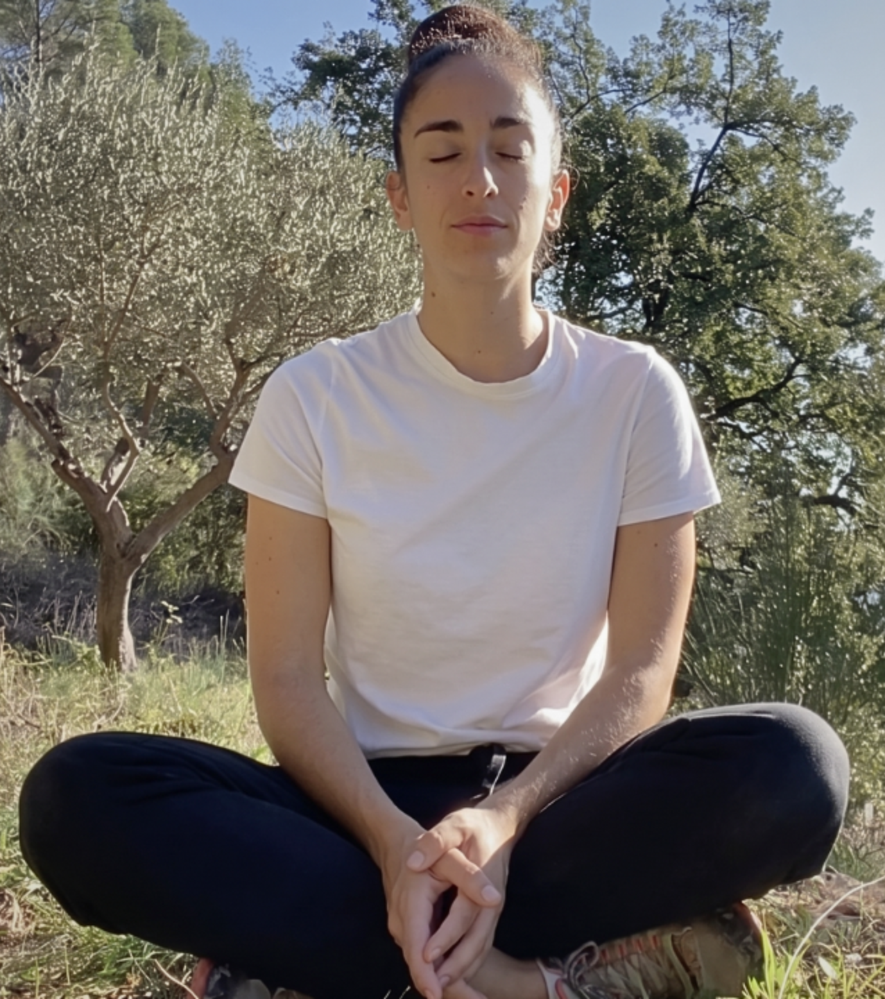 Margaux Magnée assise en tailleur dans l'herbe, les yeux fermés, en pleine respiration