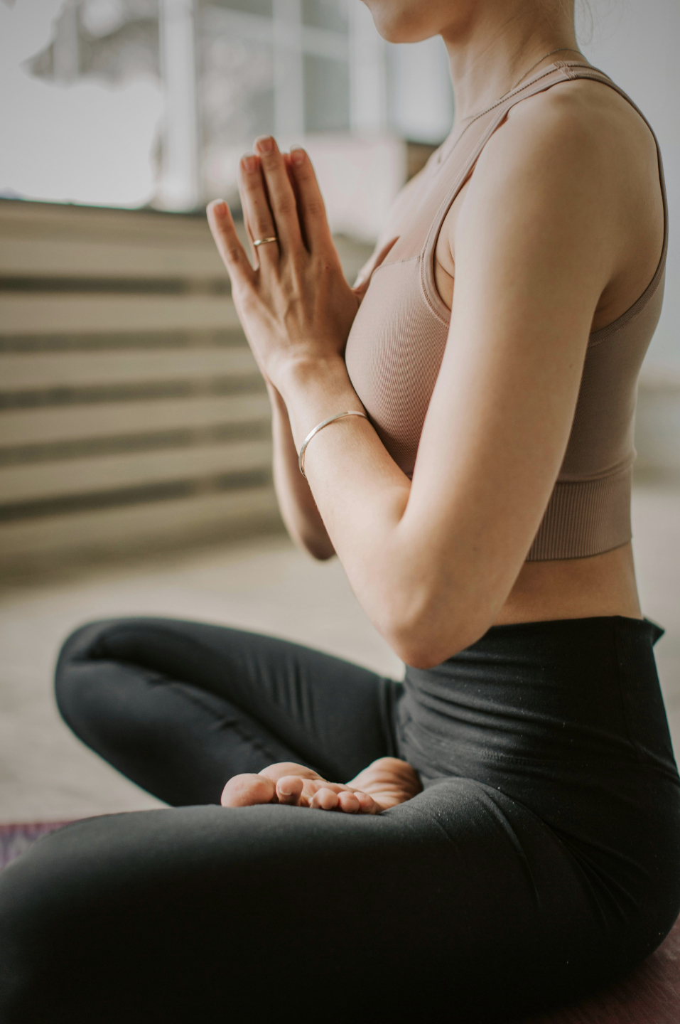 Margaux assise en tailleur, mains jointes en prière, pendant une séance de respiration
